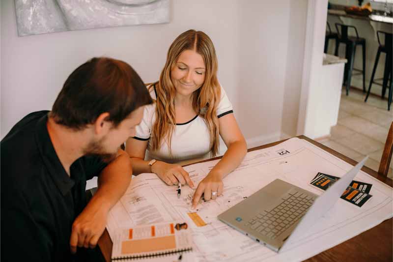 Homeowners reviewing plumbing maintenance plans at a table with service paperwork and a laptop